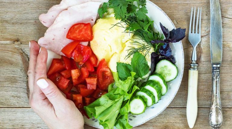 A plate full of tomatoes, salad and ham.