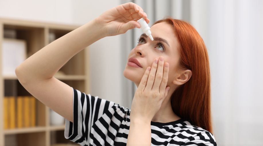 A woman putting eye drops in her eyes.