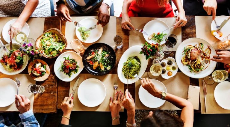 A group of people eating family-style dishes on a long table.