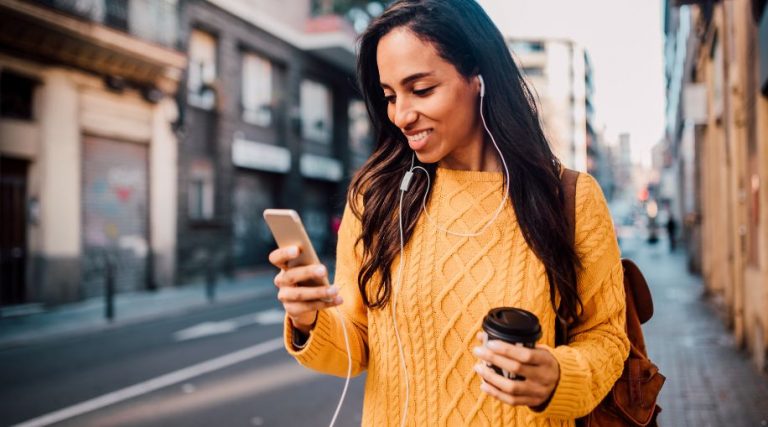 A woman in a yellow sweater using a cell phone.